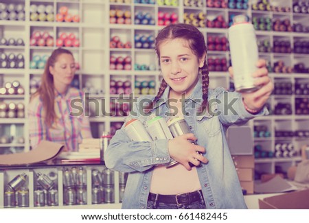 Mother and happy daughter holding spray with color paint can in art department