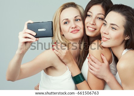 Best moments concept. Group of happy smiling and laughing friends in casual clothing taking selfie with smartphone. Urban street style. Studio shot