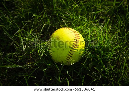 Yellow baseball on a green grass on the field