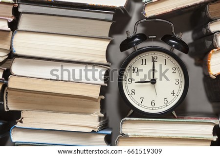 alarm clock showing nine o'clock among stack of old books background Royalty-Free Stock Photo #661519309