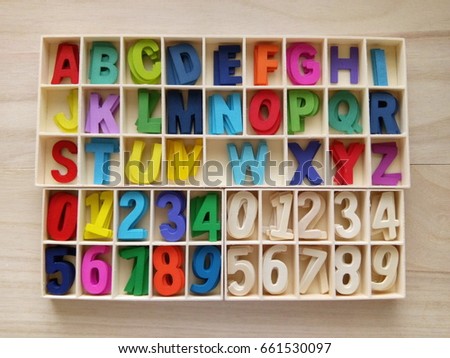Colorful of alphabet and number in the box on a wooden background. underexposed 