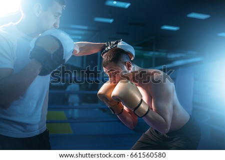 Boxer in gloves exercises with sparring partner