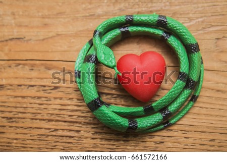 black and green snake Winds around red hearts in the middle. wooden background. medical background. 