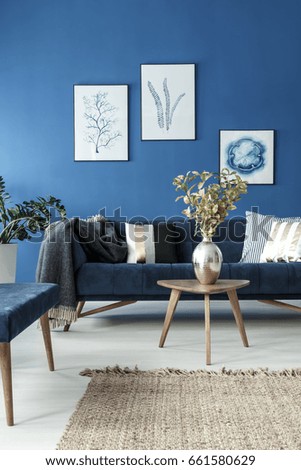 End table with flower vase and retro sofa in blue stylish room
