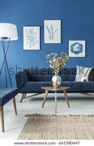 Stylish end table with flower vase and vintage sofa in cyan living room