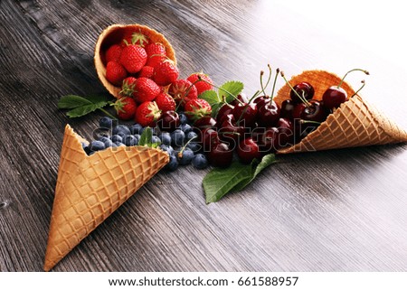 Berries in waffle cones - strawberry, blueberry and black cherry on grey background