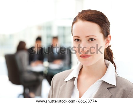 Charismatic businesswoman standing in the foreground while her team his working in the office