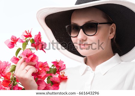 Portrait of beautiful young woman in hat with red flowers on white background