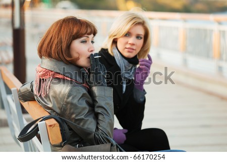 Two young women sitting on a bench.