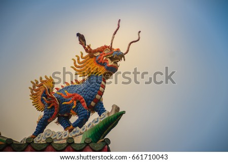 Chinese dragon-headed unicorn statue on the temple roof. Kylin or Kirin on roof in Chinese temple. Royalty-Free Stock Photo #661710043