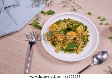 delicious delicious spaghetti with shrimps and basil on a plate on a wooden background
