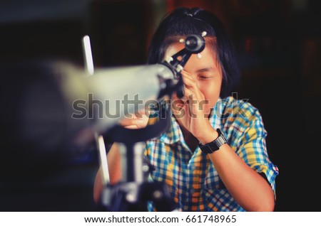 Thai student looking through telescope to see the sky 