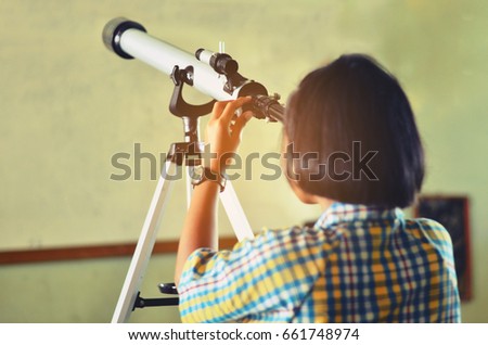 Thai student looking through telescope to see the sky 