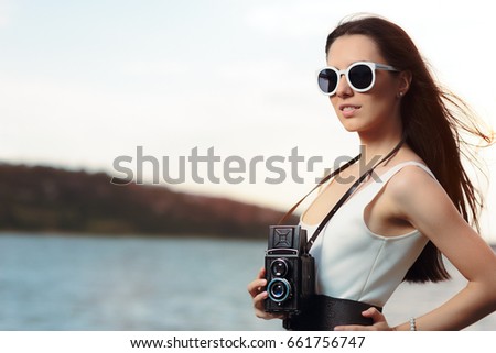 Retro Woman with Vintage Photo Camera on a Beach  - Beautiful girl in a white dress on the seashore near a boat
