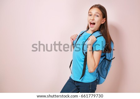 Cute pretty girl with schoolbag on color background