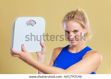 Fit fitness woman with scale. Frustrated angry blonde girl holding weight scales. Time for slimming weightloss, diet and healthy lifestyles concept