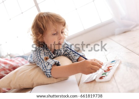 Nice serious boy holding a painting brush