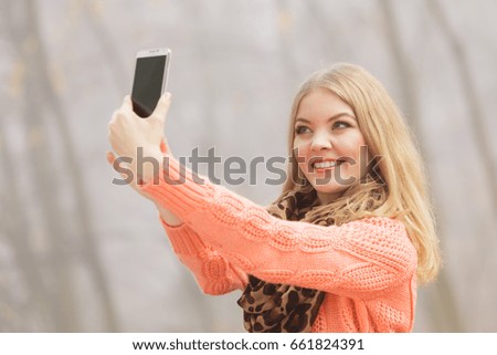 Happy fashion woman in fall autumn park taking selfie self photo picture. Pretty joyful young girl in sweater pullover photographing.