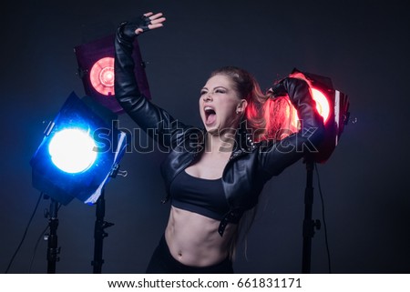 Girl in a leather jacket on stage and three colored spotlights