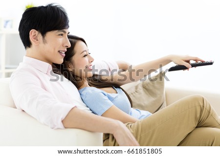 smiling  young couple watching tv  in living room