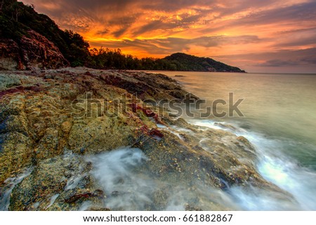 A long exposure picture Beautiful Scenery cloudy Sunset With Stone and wave As Foreground