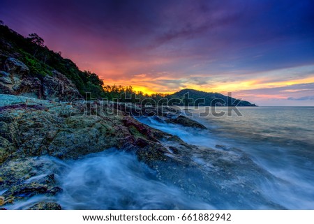 A long exposure picture Beautiful Scenery cloudy Sunset With Stone and wave As Foreground
