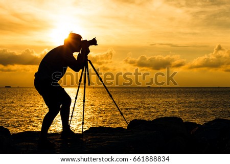 Silhouette of man taking photo with tripod
