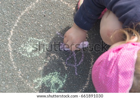 closeup on the pavement chalk and draws a baby girl.