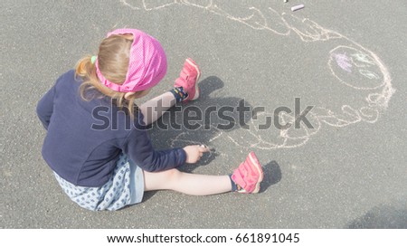 the baby girl draws mother on the pavement a Sunny day.