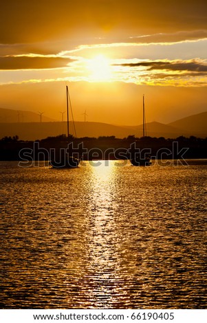 two sailboats anchored at sunset