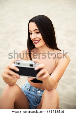 Girl taking selfie with retro camera on beach