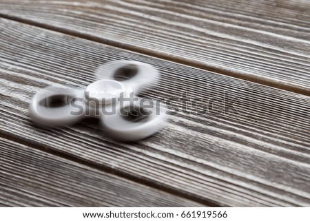 Spinning in motion of a popular white toy spinner on a wooden table. Developing, meditation, relaxation.