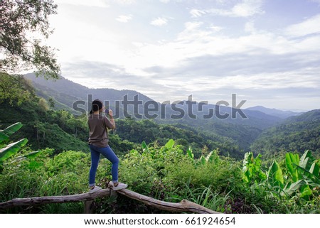 Women take mountain pictures with mobile phones.
