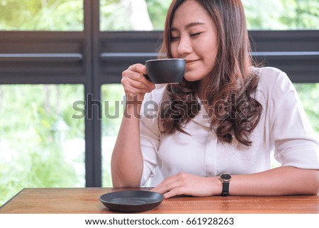 Closeup image of Asian woman close her eyes smelling and drinking hot coffee with feeling good in loft cafe