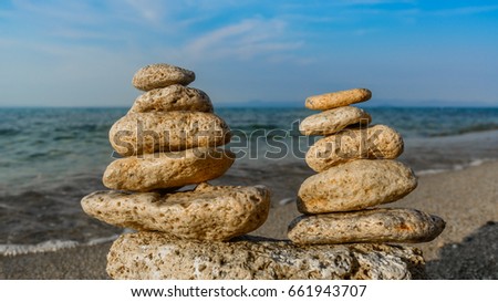 Zen stone balance, harmony on beach for perfect meditation. Calm sea meditate background with pyramids of rocks. Two sand color five stones stacks standing on sand for concept of relaxation.