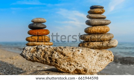 Colorful stones stacks (five and seven) standing on sand for concept of relaxation. Zen stone balance, harmony on beach for perfect meditation. Calm sea meditate background with two pyramids of rocks.