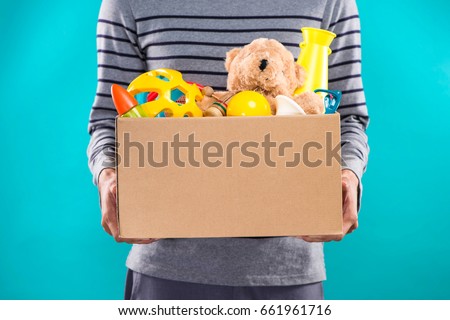 Male volunteer holding donation box with old toys. Royalty-Free Stock Photo #661961716