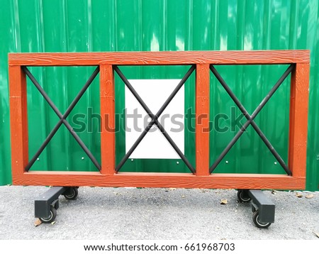 Wooden barrier to prevent parking in front of a green corrugated panel.