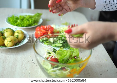 Female hands are cooking vegetable salad at the kitchen. Close-up picture, selective focus.