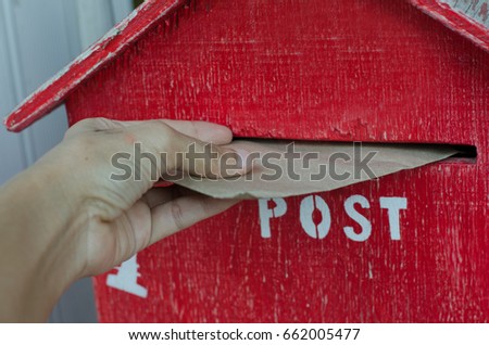 Red mailbox hand holding envelope sending letter back home to friends and family. Classic retro life in digital age.