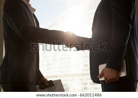 Business handshake, two businessmen wearing suits handshaking after negotiations, male partners shake hands, big city building at background, hiring accounting firm, support, help. Close up side view Royalty-Free Stock Photo #662011486