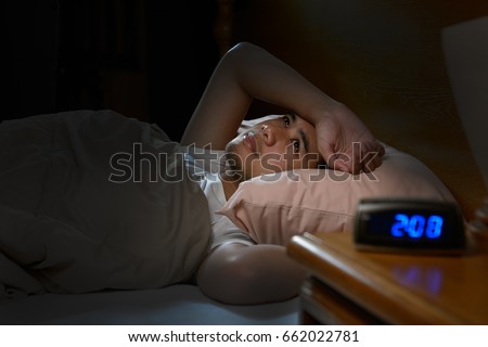 Depressed man suffering from insomnia lying in bed Royalty-Free Stock Photo #662022781