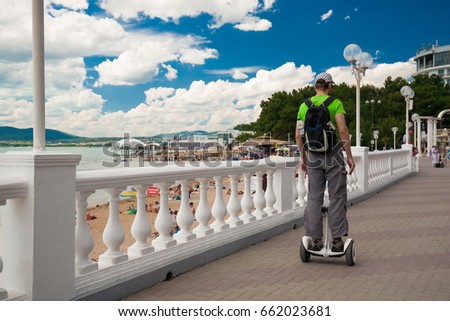 Beautiful man, has happy face, green t-shirt, sunglasses, rides electric hoverboard. Alternative sport transport. Portrait urban city. Hobby concept.