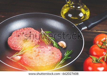 Raw cutlets pan with rosemary and garlic. Wooden brown background