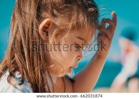 Portrait of a charming little girl on the beach in summer