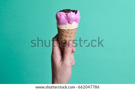 Ice cream cone in hand on blue bright background. Summer desserts. Top view.