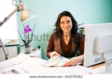 Smiling architect with color pallete on her desk. Project and interior design
