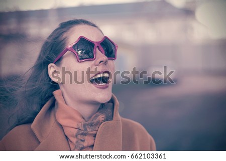 Young smiling woman with vivid emotions in sunglasses in the form of a star