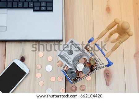 Money in a  cart with a mobile phone and a laptop is placed on a wooden floor. Business Ideas for On-line. Top view.