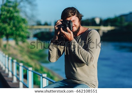 Hipster man taking a photo on retro camera outdoor